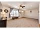 A comfortable living room features neutral carpeting, a ceiling fan, and a large window at 2091 Basil St, Strasburg, CO 80136