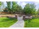 Landscaped backyard with a fire pit, stone wall seating, green grass, and a charming wooden fence at 6040 Virgil St, Arvada, CO 80403