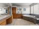 Bathroom showcasing a soaking tub, separate vanity area, glass block window, and tile flooring at 6040 Virgil St, Arvada, CO 80403