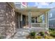 Close-up of a covered porch with brick accents, a 'Welcome' sign, and green landscaping at 6040 Virgil St, Arvada, CO 80403