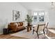 Bright living room with a large bay window, brown leather couch, modern furniture, and light wood flooring at 12776 Yates Cir, Broomfield, CO 80020