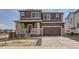 Two-story home with brown siding, brick accents, and a two-car garage on a sunny day at 798 Sawdust Dr, Brighton, CO 80601