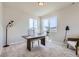 Bright home office with a wooden desk, comfortable seating, and natural light from two windows at 798 Sawdust Dr, Brighton, CO 80601