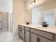 Elegant bathroom with double sinks, gray cabinetry, quartz countertops, and marble-look tile floors at 798 Sawdust Dr, Brighton, CO 80601