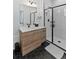 Modern bathroom with a walk-in shower, hex tile flooring, and a light wood vanity at 3553 W 63Rd Ave, Denver, CO 80221