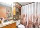 This bathroom offers granite counters, a sink, a decorative shower curtain, and shelfing for towels at 5106 Eagle Ct, Denver, CO 80239