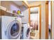 This laundry room has a washer, a dryer, shelving for detergent, and an entrance to a bathroom at 5106 Eagle Ct, Denver, CO 80239