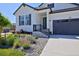 Inviting front exterior featuring manicured landscaping and a welcoming entrance with charcoal gray garage doors at 1160 Spencer Pl, Erie, CO 80026