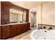 Luxurious bathroom featuring a soaking tub, a double vanity with granite countertops, and wooden cabinetry at 730 Crescent Ln, Lakewood, CO 80214