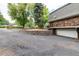 Stone facade home with driveway, retaining wall, garage, and lush green trees at 730 Crescent Ln, Lakewood, CO 80214