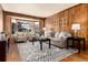 Bright living room with hardwood floors, wood paneling, neutral furniture, and a large bay window at 730 Crescent Ln, Lakewood, CO 80214