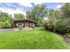 The matching shed with stone accents has a green lawn and an adjacent stream at 730 Crescent Ln, Lakewood, CO 80214