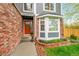 Welcoming front entrance featuring a brick facade, a vibrant orange door, and beautiful landscaping with a bay window at 1101 Ridgeview Cir, Broomfield, CO 80020