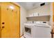Functional laundry room with modern washer and dryer units and storage shelf at 1101 Ridgeview Cir, Broomfield, CO 80020