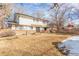 Backyard with a grassy area, patio, and partial snow cover, surrounded by mature trees at 8736 E Easter Ave, Centennial, CO 80112