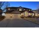 Inviting two-story home with a spacious three-car garage and charming front porch, illuminated at dusk at 1015 Graland Pl, Highlands Ranch, CO 80126