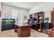 Well-lit home office with a large wooden desk, built-in shelving, and an aquarium for a relaxing ambiance at 1015 Graland Pl, Highlands Ranch, CO 80126