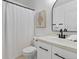 A clean and crisp bathroom with a white vanity, a modern curved mirror, and a shower with a white curtain at 2768 Florence St, Denver, CO 80238