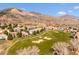 Stunning aerial view of a neighborhood on a golf course, nestled against picturesque mountains under a clear blue sky at 16611 Red Cliff Cir, Morrison, CO 80465