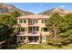 Spacious home with multiple balconies, large windows, and a backyard patio, set against a backdrop of rolling mountains at 16611 Red Cliff Cir, Morrison, CO 80465