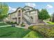 A light-green, two-story condo featuring stone accents and stairs to the second-story entrance at 5800 Tower Rd # 1201, Denver, CO 80249