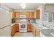 Well-lit kitchen featuring wood cabinets, white appliances, and a view from the sink area at 5800 Tower Rd # 1201, Denver, CO 80249