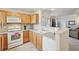 Kitchen with wood cabinets, white appliances, and an open layout connecting to the living area at 5800 Tower Rd # 1201, Denver, CO 80249