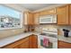 Bright kitchen with wooden cabinets, white appliances, and a window offering natural light and neighborhood views at 5800 Tower Rd # 1201, Denver, CO 80249