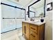 Modern bathroom with a wooden vanity, glass-enclosed shower, and black hardware accents at 10226 E Fair Pl, Englewood, CO 80111