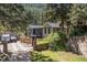 Home exterior surrounded by lush trees, with a garage, stone wall, and driveway at 55 Two Moon Rd, Idaho Springs, CO 80452