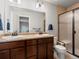 Bathroom featuring double sinks, wood cabinets, and glass shower at 14823 W 70Th Dr # A, Arvada, CO 80007