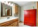 Bathroom with a wood vanity, large mirror, bright red cabinet, and stylish lighting at 41504 Vista Ridge, Parker, CO 80138