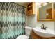 Small bathroom with a cabinet, toilet, white sink, stylish mirror, and patterned shower curtain at 41504 Vista Ridge, Parker, CO 80138