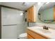 Bathroom featuring a shower with glass doors, wood vanity with a sink, and a round mirror at 41504 Vista Ridge, Parker, CO 80138
