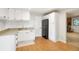Kitchenette featuring white cabinetry, a black refrigerator, a mosaic backsplash, and a stone fireplace in the background at 41504 Vista Ridge, Parker, CO 80138
