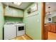 Bright laundry room with green walls, cabinets, a clothes rack, and a washer and dryer at 41504 Vista Ridge, Parker, CO 80138