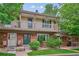 Charming two-story townhome featuring a brick facade, balcony, green door and a well-maintained front yard at 6880 E Appleton Cir, Centennial, CO 80112