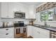 Modern kitchen with white cabinets, stainless steel appliances, and a view of the outdoors at 6880 E Appleton Cir, Centennial, CO 80112