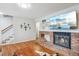 Open-concept living room featuring a brick fireplace, hardwood floors, and staircase at 6880 E Appleton Cir, Centennial, CO 80112