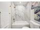 A white tiled tub and shower is complemented with gold fixtures and a modern toilet in a bathroom setting at 1896 S Marshall Cir, Lakewood, CO 80232