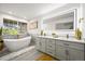 Spa-like bathroom features a soaking tub, marble accents, a large mirror, and a double sink vanity with gold fixtures at 1896 S Marshall Cir, Lakewood, CO 80232