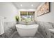 Bright bathroom with a soaking tub, marble tile surround, gold fixtures, and an abundance of natural light at 1896 S Marshall Cir, Lakewood, CO 80232