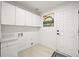Functional laundry room features white cabinetry, tile flooring, and a utility sink for added convenience at 1896 S Marshall Cir, Lakewood, CO 80232