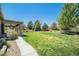 Beautiful backyard featuring a lush green lawn, mature trees, and a covered patio for relaxation and entertaining at 26004 E Elmhurst Pl, Aurora, CO 80016
