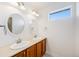 Bright bathroom featuring double sinks with wood cabinets, framed mirrors and overhead lighting at 26004 E Elmhurst Pl, Aurora, CO 80016