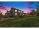 Exterior shot of a large, well-maintained home with a stone facade, covered patio, and a lush green lawn at dusk at 26004 E Elmhurst Pl, Aurora, CO 80016