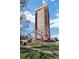 Tall apartment building with balconies, blue sky, and green landscaping at 100 Park W Ave # 1606, Denver, CO 80205