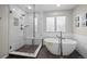 Modern bathroom with a freestanding tub, walk-in shower with bench, and a window for natural light at 5272 W Capri Pl, Littleton, CO 80123