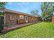 Spacious backyard with a wood deck, green lawn, and a stack of firewood near the house at 6223 W Flora Pl, Denver, CO 80227