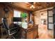 A gorgeous wood paneled home office features a large executive desk and an adjacent view to a relaxing outdoor space at 6223 W Flora Pl, Denver, CO 80227